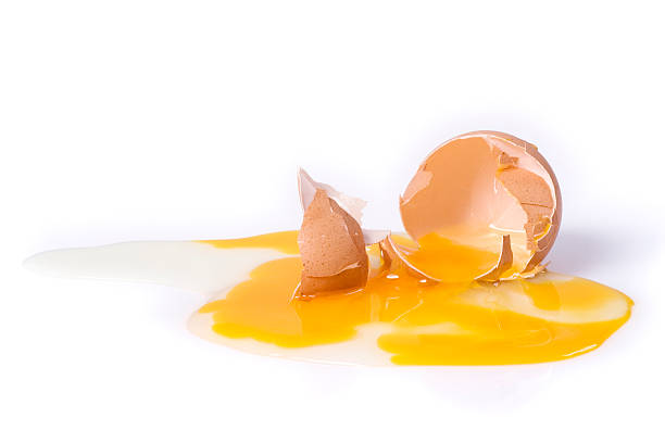 A broken brown egg on a white background stock photo