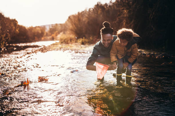 Father and son catching fish with fishing net in river