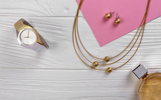 goldene und silberne uhr mit goldkette auf weißem holz hintergrund - pink perfume bracelet necklace stock-fotos und bilder