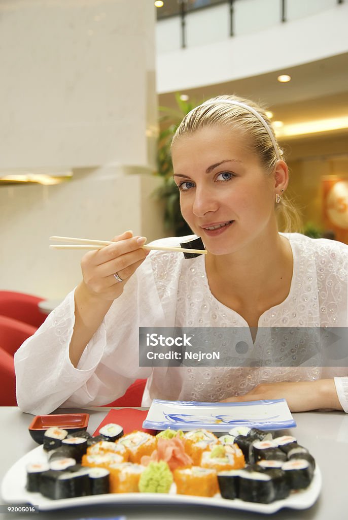 Belle fille mange des sushis dans un restaurant - Photo de A la mode libre de droits