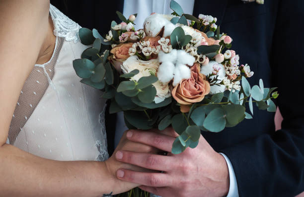 istock Bride and groom holding wedding bouquet together 920056008
