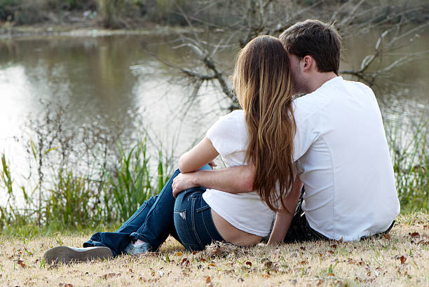 istock Young pair sitting on bank of lake 92006307
