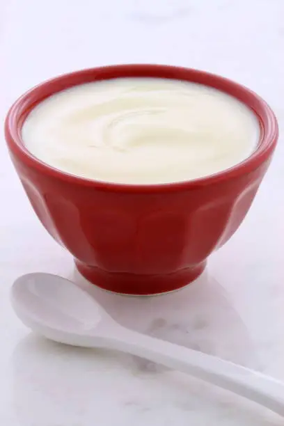 Delicious, nutritious and healthy fresh plain yogurt on vintage carrara marble setting.