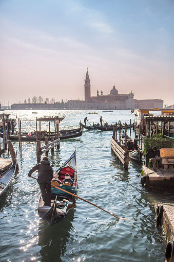 Venice, Italy - February 11, 2016. Tourists taking a Gondola ride out to sea with  San Giorgio Maggiore church in background
