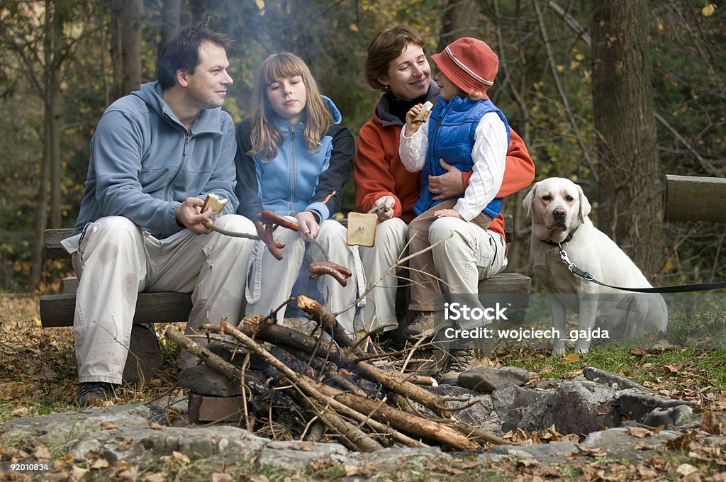 Famille heureuse avec chien près du feu de camp - Photo de Bâton de bois libre de droits