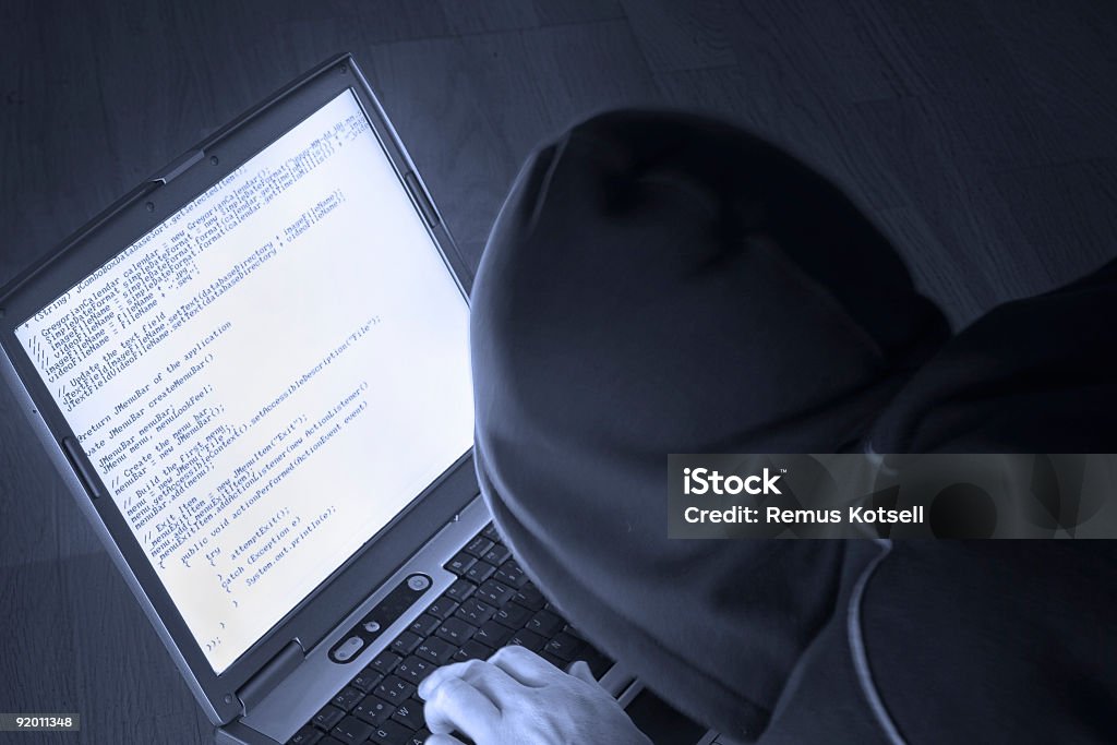 Anonymous person hacking into a computer A person hacking in a dark place on a laptop Color Image Stock Photo