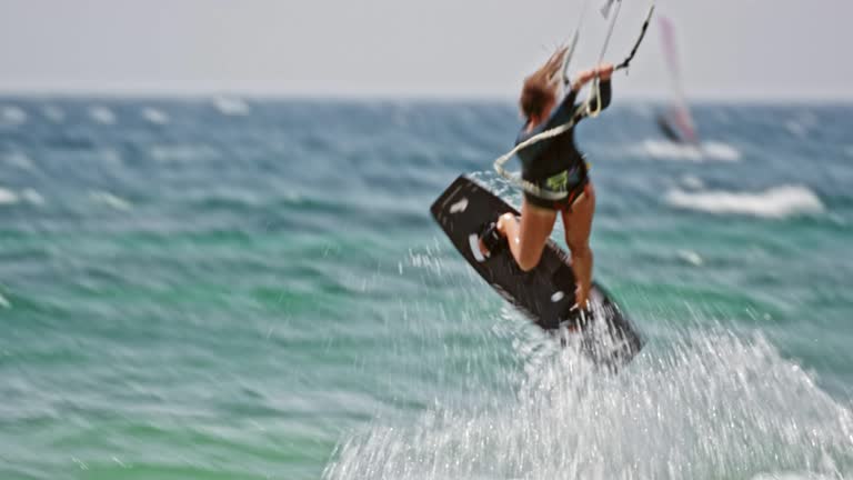 Female kiteboarder jumping into the air and doing a turn