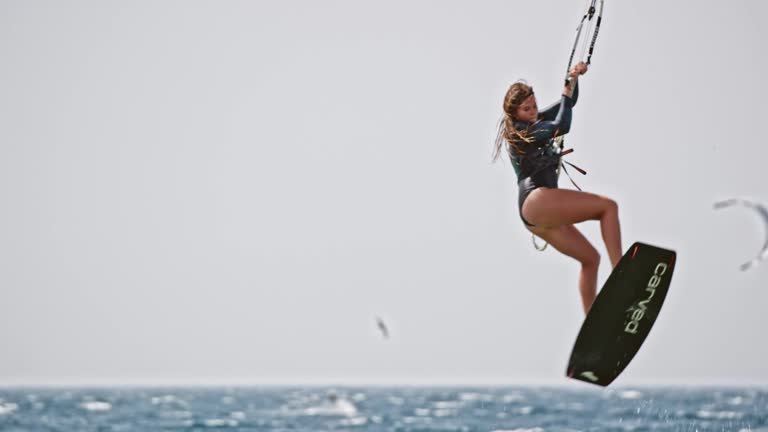 SLO MO Female kiteboarder jumping into the air and turning