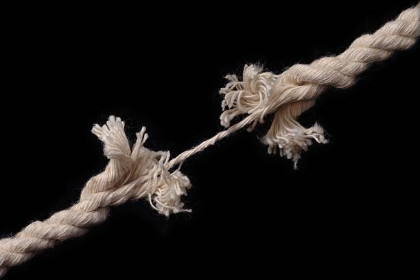 A rope that is only hanging together by a thread stock photo