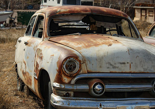 photo of a variety of rusty vintage cars in a junk yard