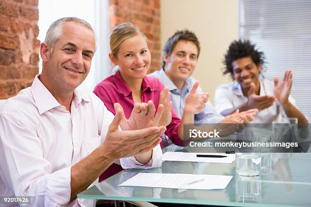 Foto de Quatro Empresários Na Sala De Diretoria Aplaudindo E Sorrindo e mais fotos de stock de 20 Anos