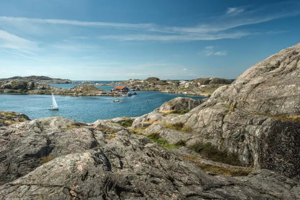 Sea landscape with yachts and rocky coastline on the South of Sweden. Southern coastline of Sweden with view at sailing-ships and rocky islands. Red fishing houses on the shore.