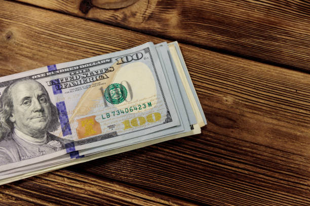 istock Stack of one hundred dollars bills on wooden desk 920188828