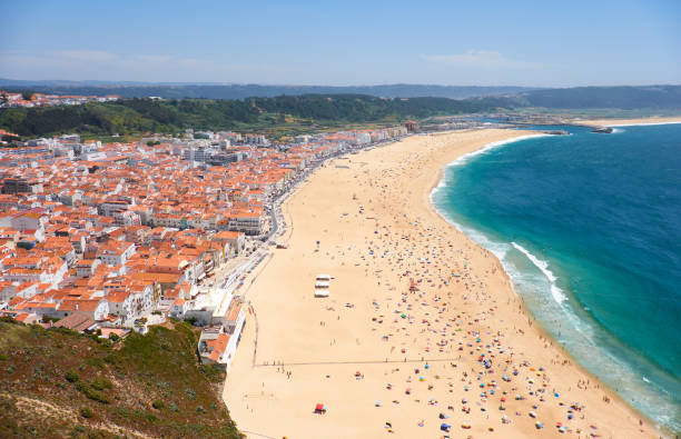 Bird's-eye view on Nazare beach riviera on the coast of Atlantic ocean with Nazare town Bird's-eye view on Nazare beach riviera on the coast of Atlantic ocean with Nazare town. Portugal nazare surf stock pictures, royalty-free photos & images