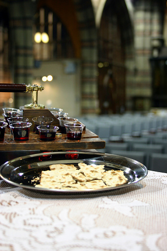 Communion bread and wine in foreground with inside of church in background