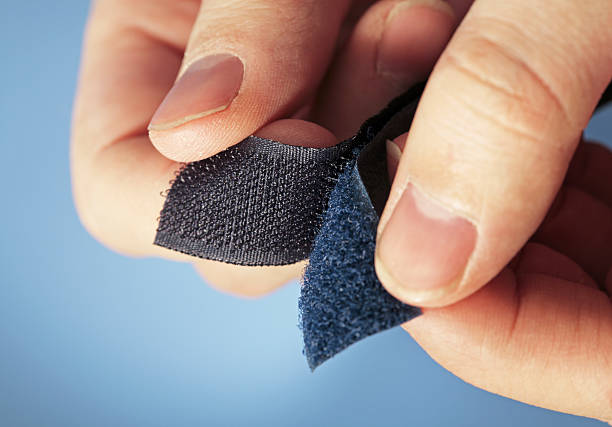 Pair of hands holding two sides of Velcro Hook-and-loop fastener aka Velcro in closeup fastening photos stock pictures, royalty-free photos & images