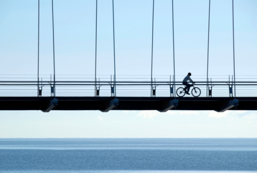 A woman riding a mountain bike across a suspension bridge near Lake Ontario, just after dawn. Please see my Canada lightbox: