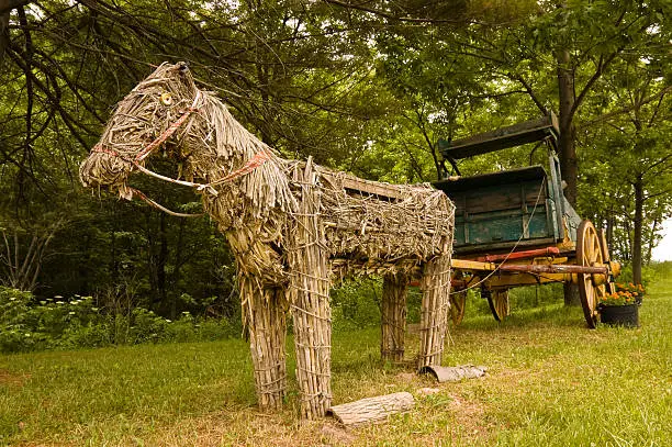 A Funky horse-drawn carriage with a horse made of hay.