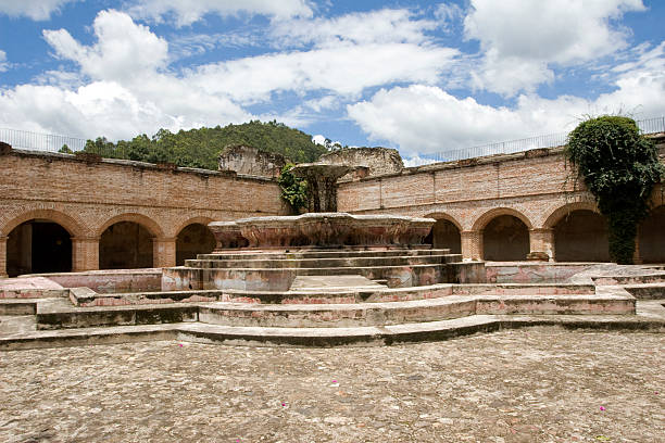 Visitors admire the intricately carved fountain at Khor Virap Monastery, set against its historic stone buildings.