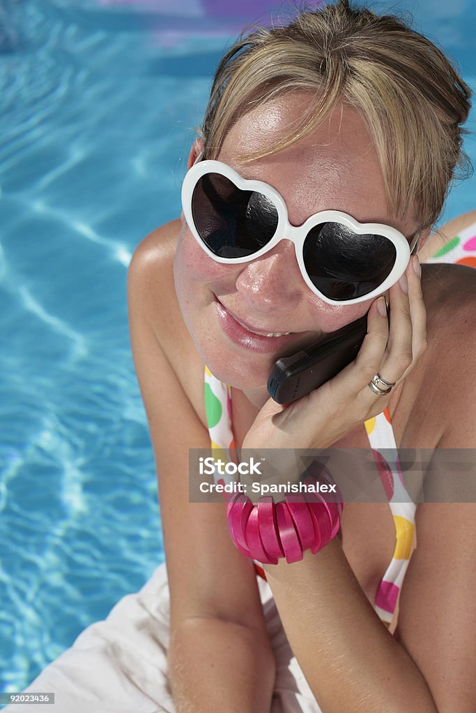 Mujer en su Cellphone junto a la piscina - Foto de stock de Actividades recreativas libre de derechos