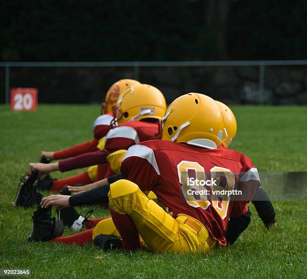 Young Football Athletes In Uniform Stretching On Grass Stock Photo - Download Image Now