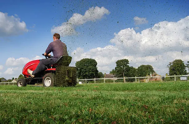 Photo of Man mowing the grass on a riding mower