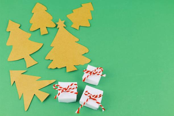 istock hand made paper Christmas trees and small presents on green background with copy space. Christmas theme. 920260518