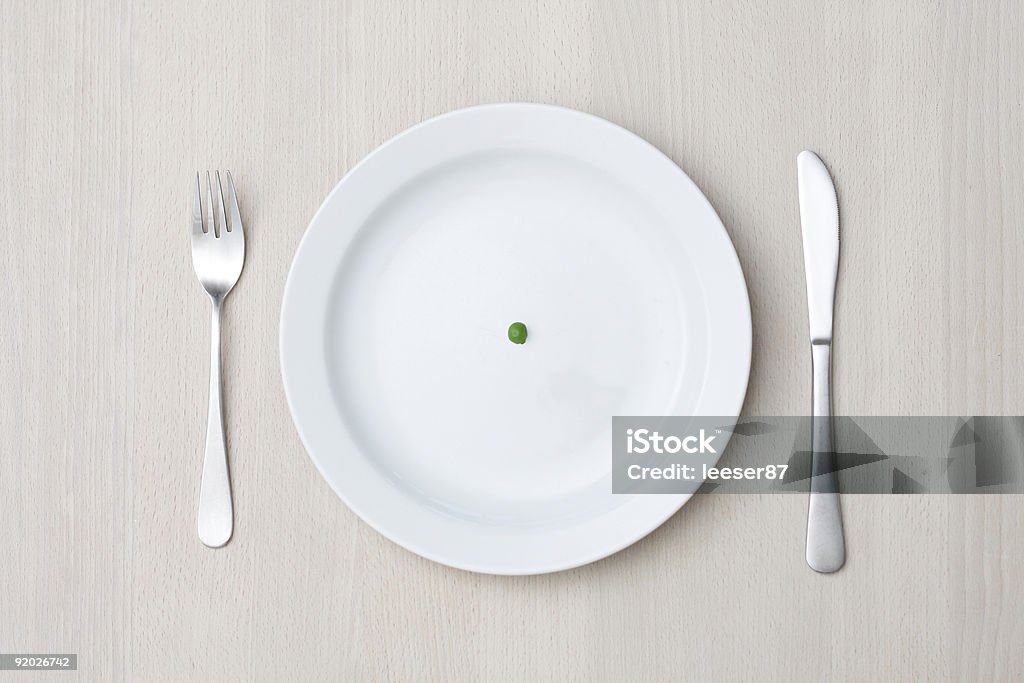 A single pea on a white dinner plate Conceptual image describing a diet Bizarre Stock Photo