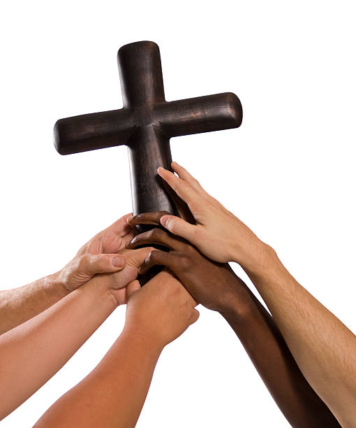 Several hands holding up steel cross stock photo