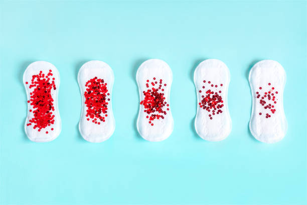 Menstrual pads with red glitter on colored background stock photo