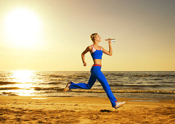 Beautiful young woman running on a beach stock photo