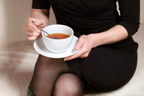 woman in black holding a cup of tea at hands stock photo
