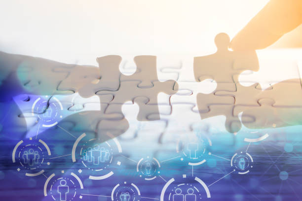 istock hand holding jigsaw piece with background of teamwork people connection 920322648