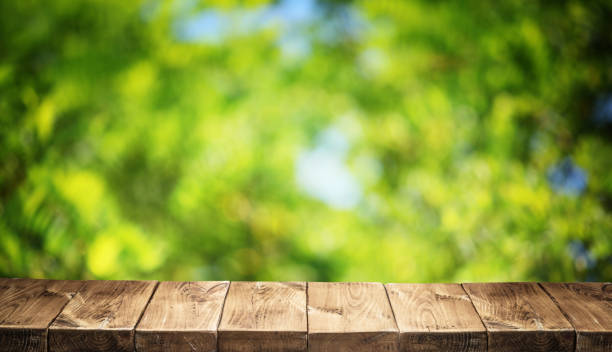 istock Old wooden table top and green foliage. 920331824