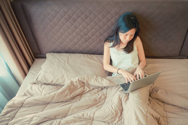 istock Stressed Asian woman using a laptop on bed in bedroom 920342596