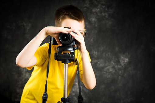 Teenage boy learning how to use a big digital camera