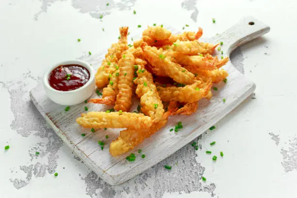 Fried Shrimps tempura with sweet chili sauce on white wooden board.