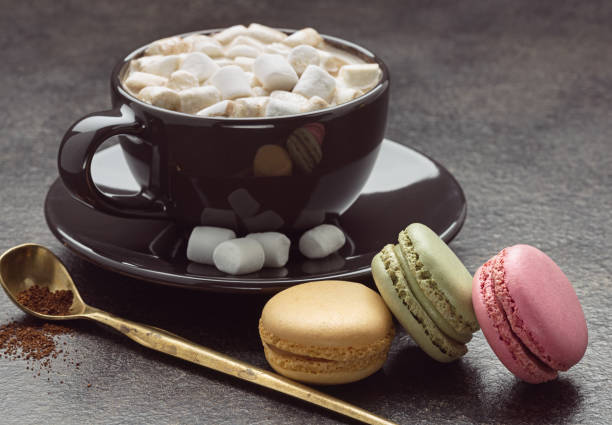 istock Cup of coffee with marshmallows, spoon and colored french macaroons, on gray background. 920357380