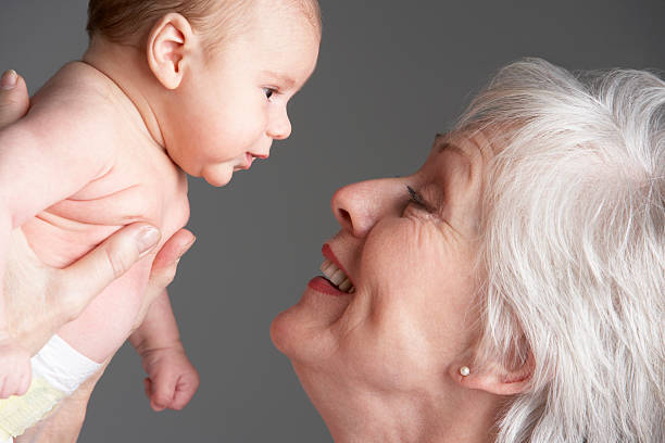 웃는 여자 및 루킹 대상쪽으로 눈을 아기 - grandmother senior adult child baby 뉴스 사진 이미지