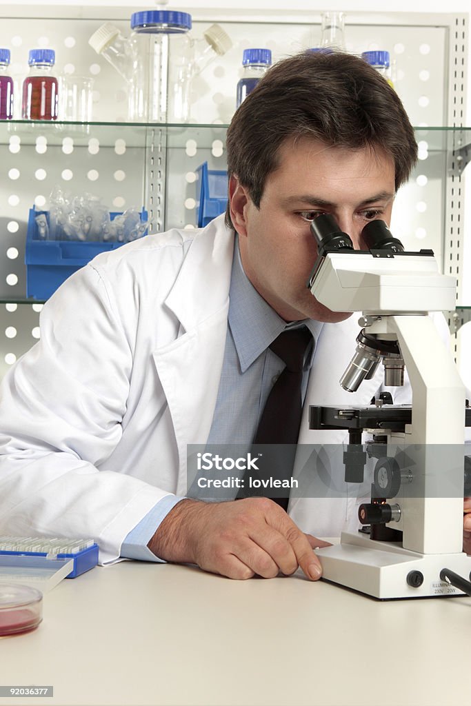 Naukowiec patrząc przez mikroskop - Zbiór zdjęć royalty-free (Analizować)