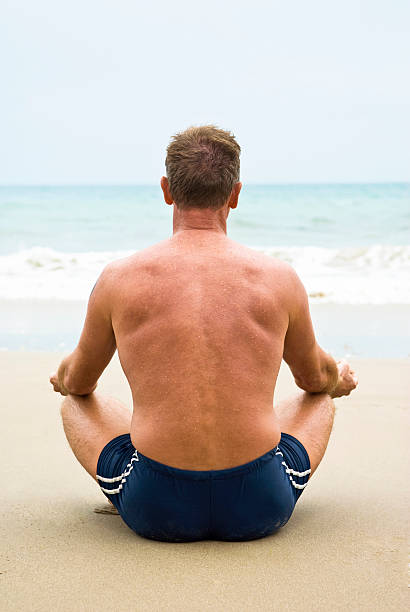 man meditating on beach. stock photo