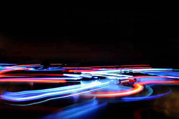 Abstract blue red horizontal lights traffic motion blur Headlights and tail lights of bumper cars in motion, long exposure nightshot. Vivid colors on a deep black backdrop. Abstract illuminated night life. Conveying movement, motion, speed, chaos. Copy space. A full frame image and horizontally oriented. The photo was taken at a funfair or amusement park. Excellent for backgrounds and designs. light trail photos stock pictures, royalty-free photos & images