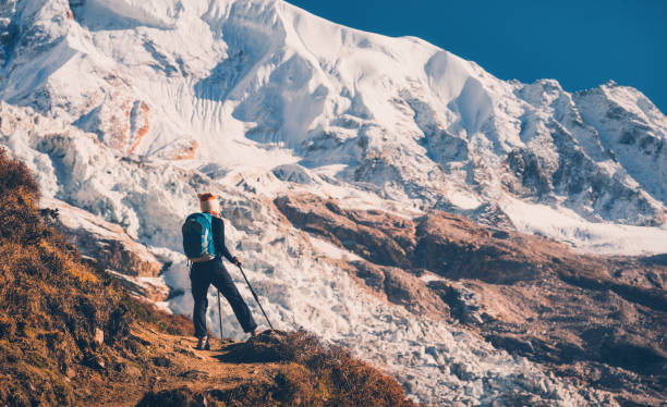 istock Standing young woman with backpack on the mountain peak against beautiful mountains and glacier at sunset. Landscape with girl, rocks with snowy peaks at bright sunny day in Nepal. Travel.Trekking 920377848