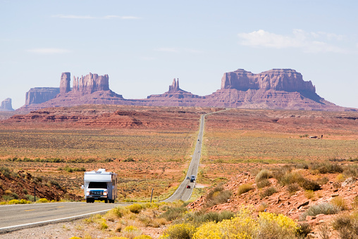 Endless highway wide angle view under beautiful cloudy summer sky to famous Monument Valley Buttes in Utah. Looking south on U.S. Route - Highway 163 from north of the Arizona–Utah border. Arizona - Utah, USA.