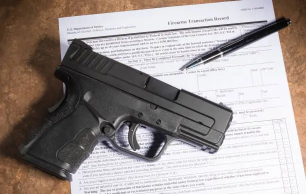 Polymer handgun and paperwork to purchase it on a beige counter