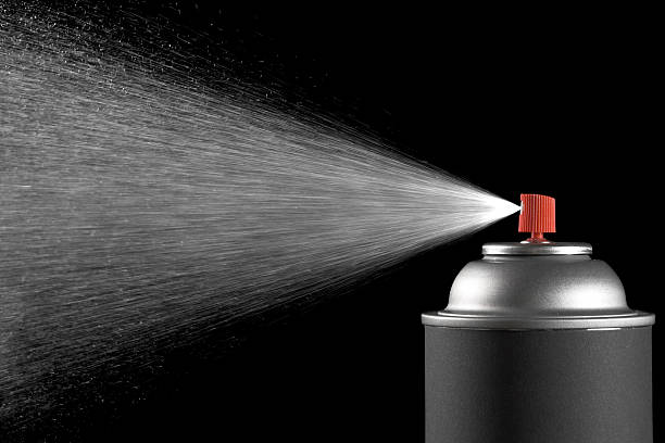 Spraying aerosol can against black background stock photo