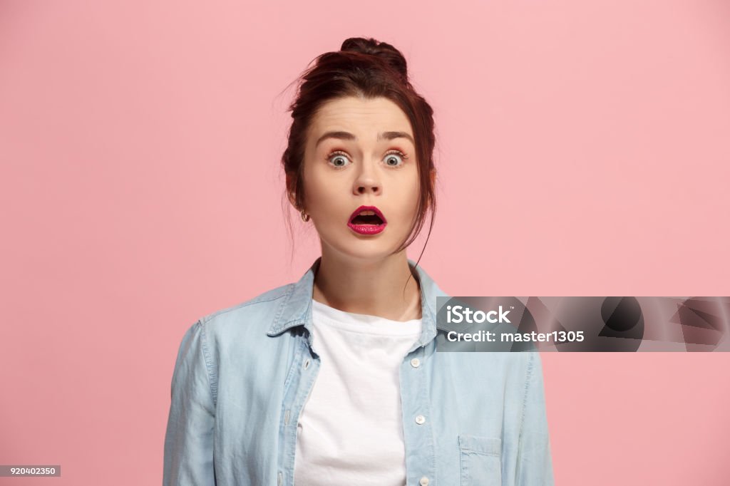 Beautiful woman looking suprised isolated on pink Wow. Beautiful female half-length front portrait isolated on pink studio backgroud. Young emotional surprised woman standing with open mouth. Human emotions, facial expression concept. Trendy colors Human Face Stock Photo