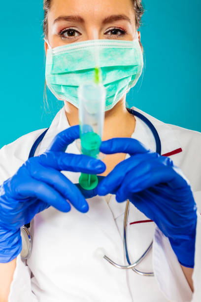 istock doctor in mask holding syringe with injection 920402680