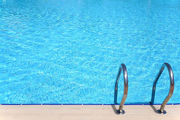istock Clear blue pool with metal stair rails 92040406