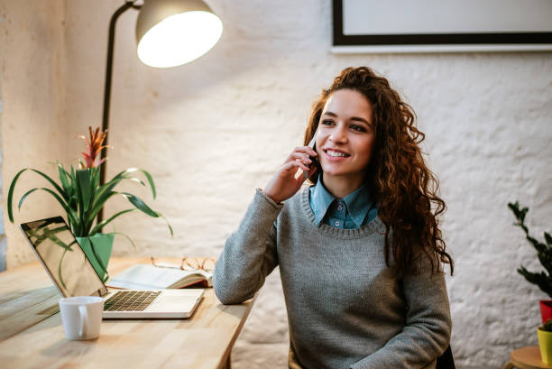 istock Young charming woman calling with cell telephone while sitting alone in office. 920408714